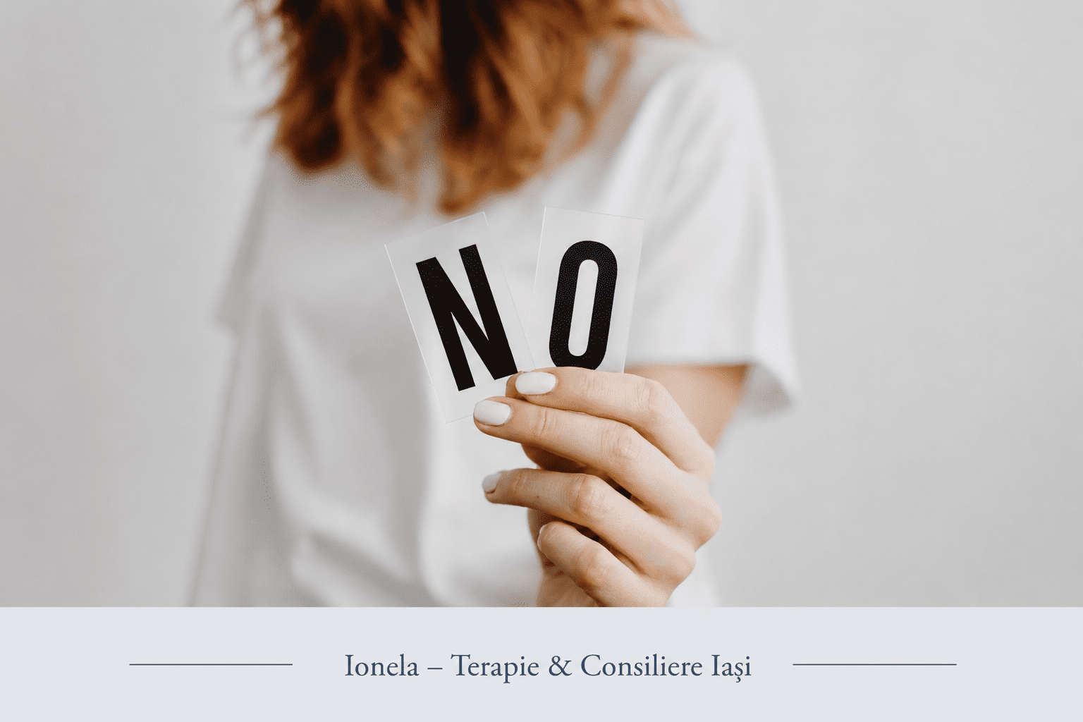 Persoană care ține în mână un cartonaș cu mesajul „NO”, simbol al limitelor personale și al exprimării propriilor nevoi.